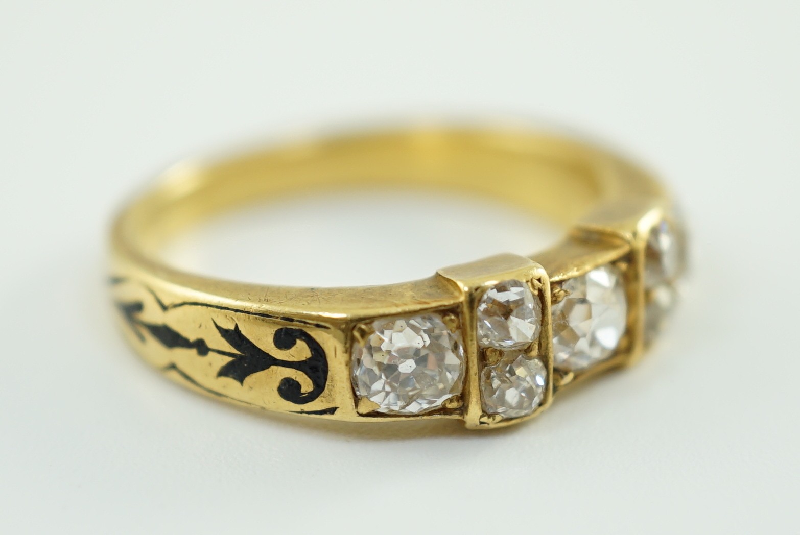 A late 19th century gold and seven stone old mine cut diamond and black enamelled cluster half hoop ring